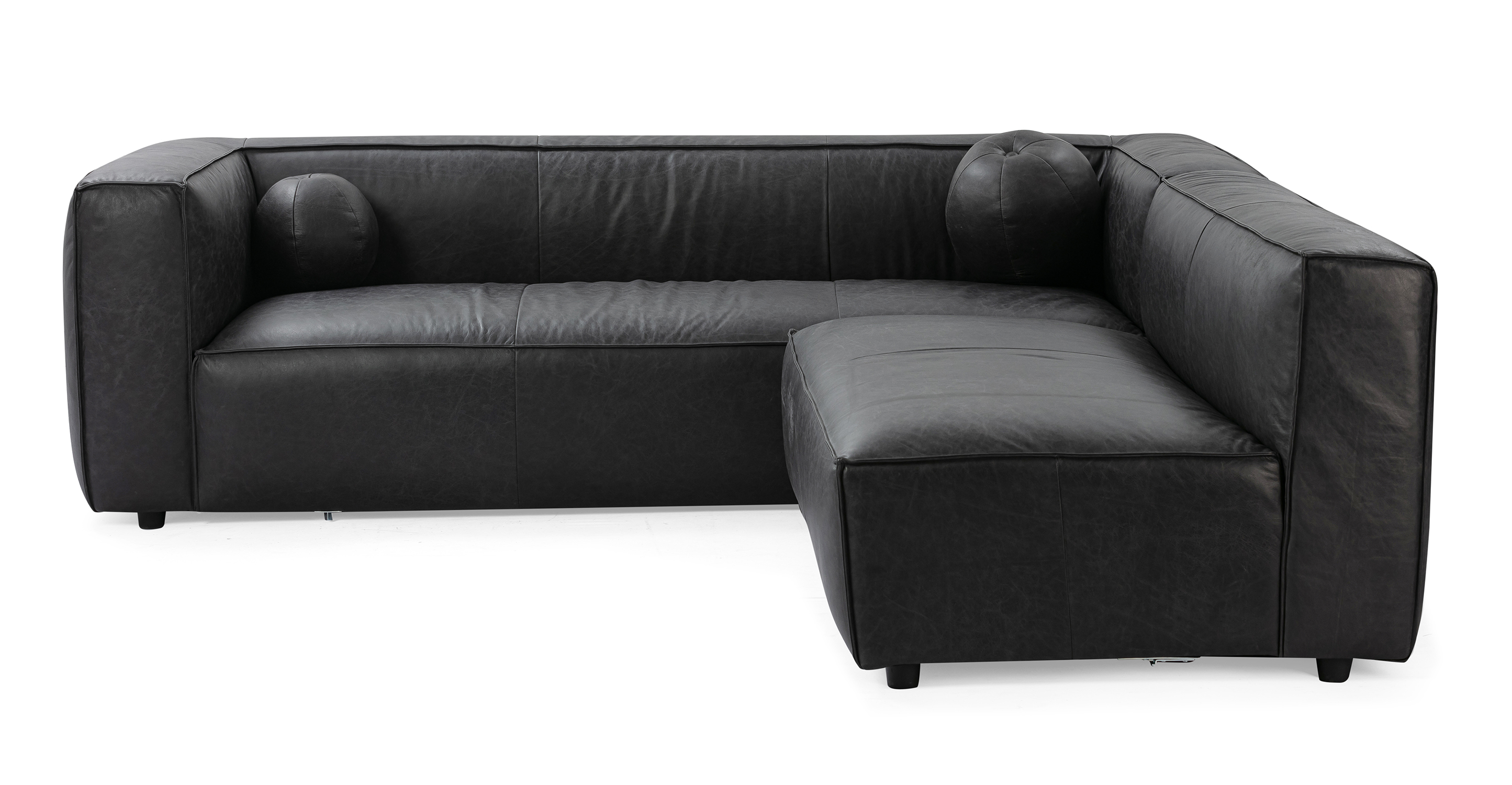 Soho Ebony 96 reversible sofa has a modern and sleek low profile. The modular set connects a 3.5 sofa with arms, to an armless sofa, creating a unique L shape. This series is supported by small black legs that allow the sofa to be close to the floor without touching. The sofa seat cushion is one thick solid piece, the arms and back are rectangle in shape. All the cushion edges are finished in piping and have interest seams to visually divide up the one seat cushion. Two matching round orb cushions are included.